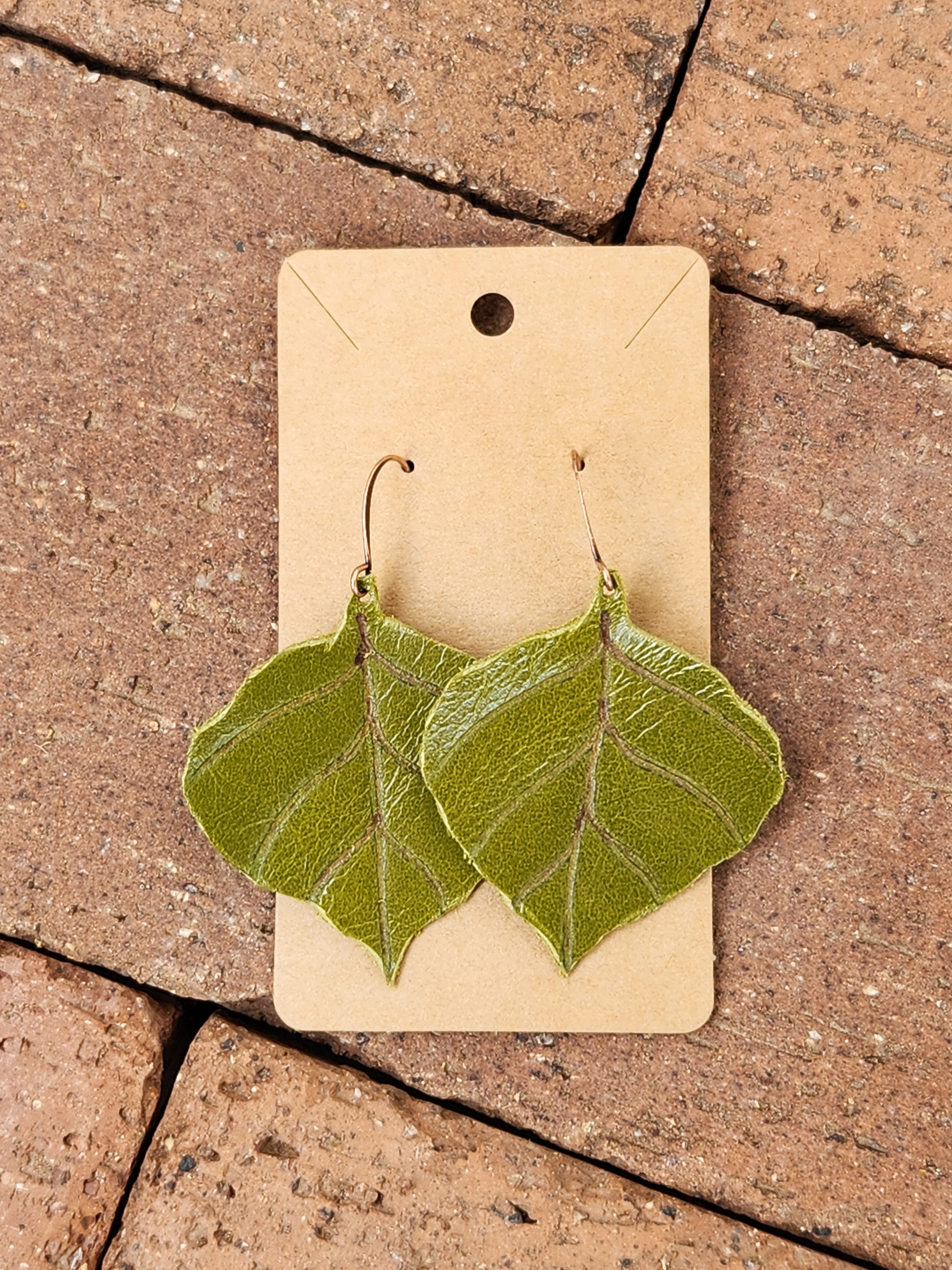 Green Leaf Leather Earrings on brick background